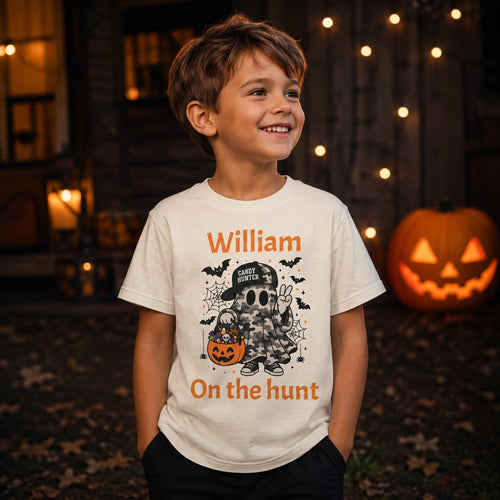 Boy wearing personalized Candy Hunter ghost Halloween t-shirt outside a decorated house with a jack-o-lantern